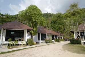 A row of bungalow-style accommodations with large windows, a paved pathway, and lush greenery. - Nature Beach Resort (Ko Chang)