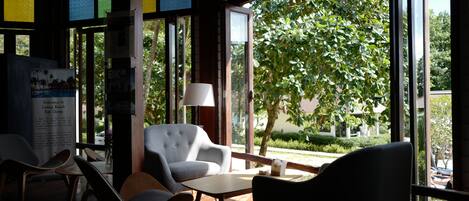 A modern interior with large windows, a white armchair, a table, and a lamp.