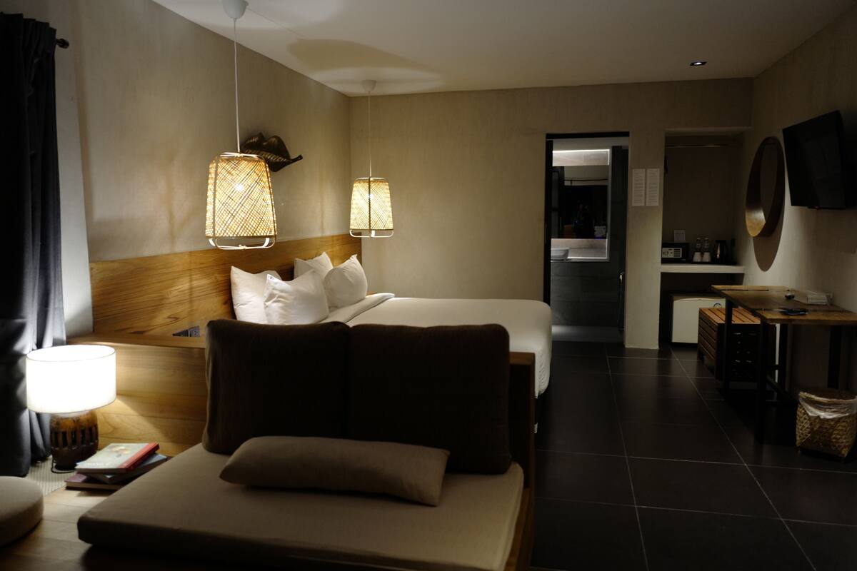A hotel room with a bed, bedside lamps, a small table, a TV, and a mirror.