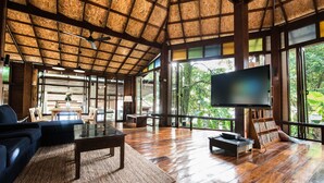 A spacious living area with a wooden floor, a large flat-screen TV, and a bookshelf. - Nature Beach Resort (Ko Chang)
