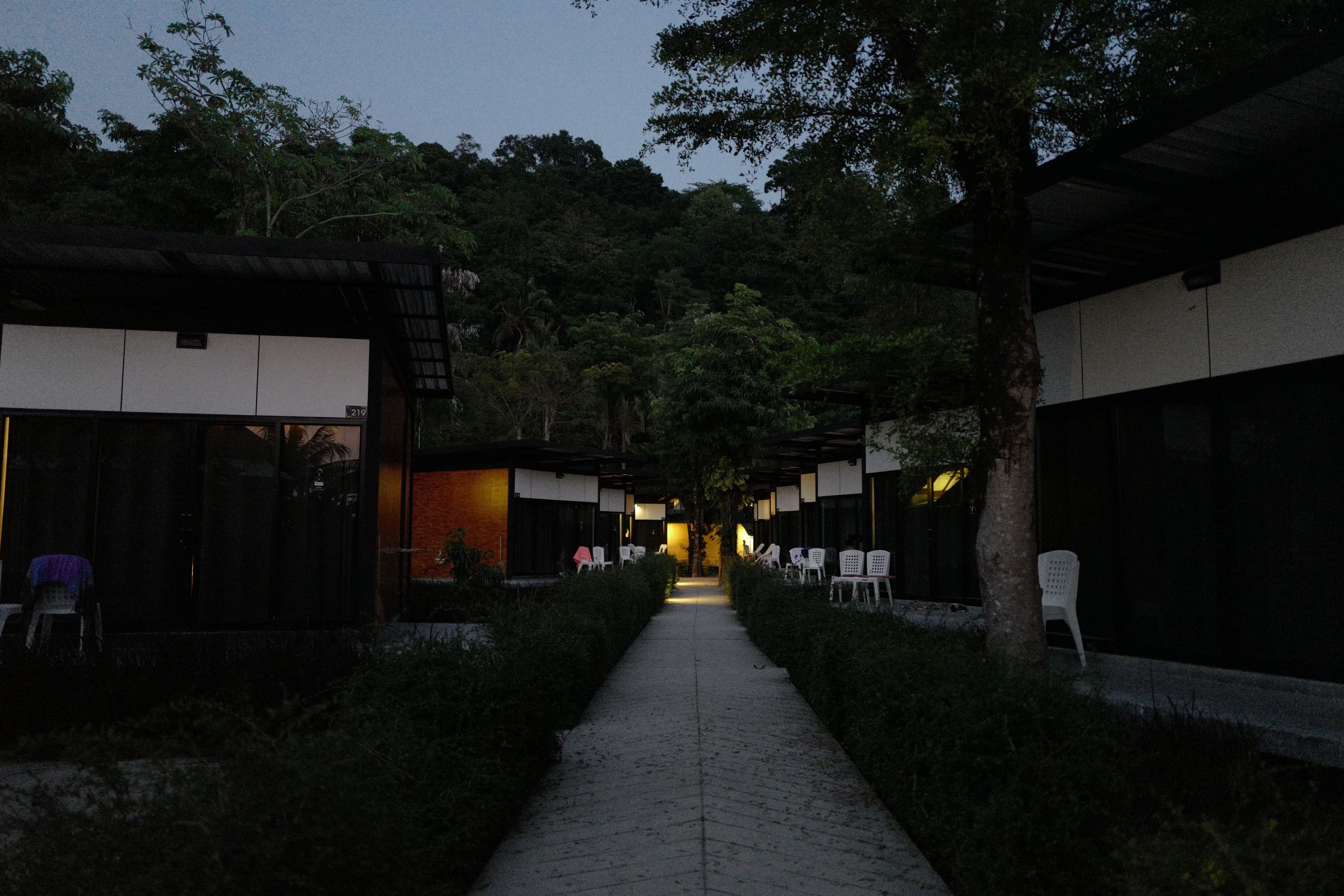 A pathway leading to a traditional-style building with a covered walkway and seating areas.