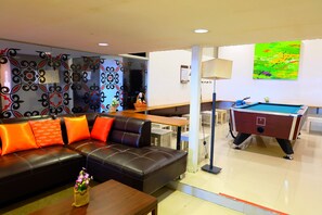 A modern living room with a leather sofa, a pool table, and a decorative wall. - Take A Nap Hotel (Bangkok)