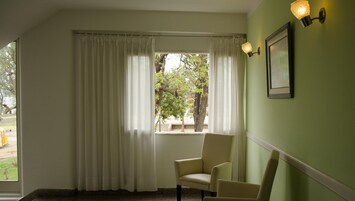 Una habitación con ventana, una silla y una lámpara fijada a la pared.