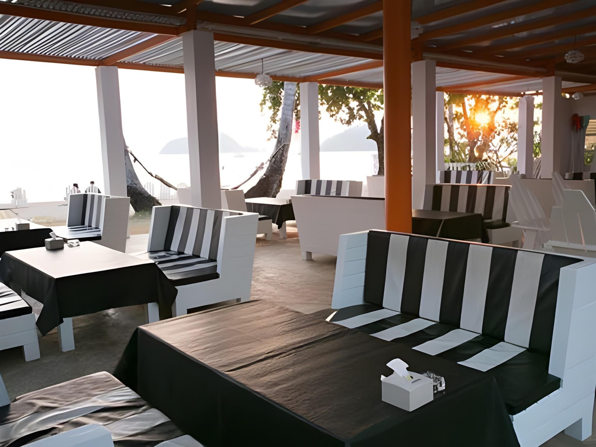 Un espace extérieur aménagé avec des tables et des chaises, un plancher en bois et une vue sur la mer.