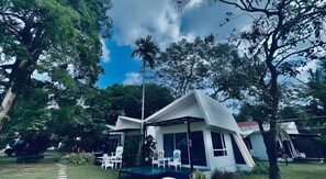 A modern building with a sloped roof, surrounded by lush greenery and trees. - Baan Koh Mak (Ko Mak)