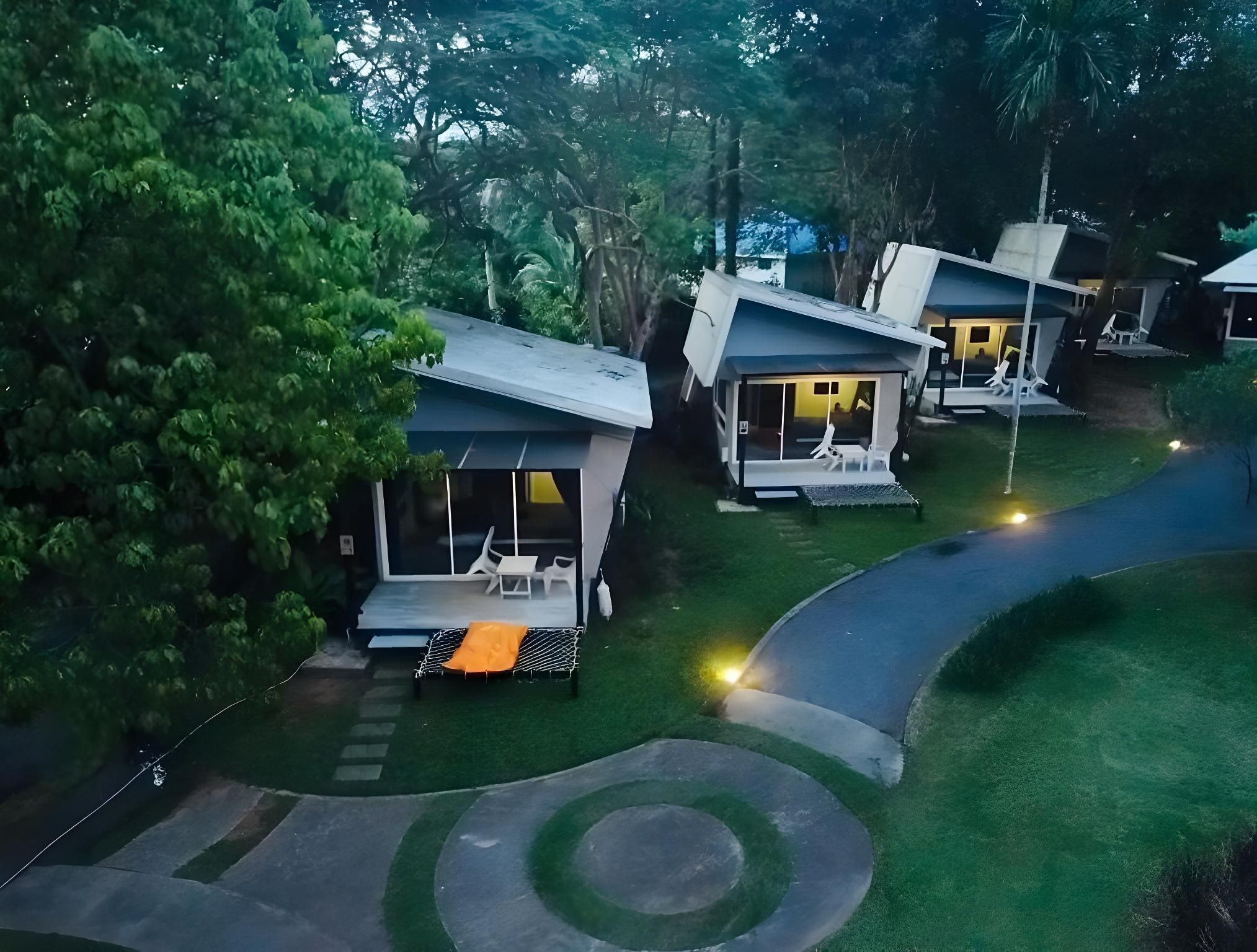 A row of modern, single-story houses with attached porches, surrounded by lush greenery.