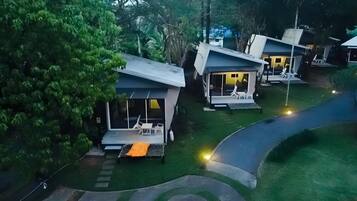 A row of modern, single-story houses with attached porches, surrounded by lush greenery.