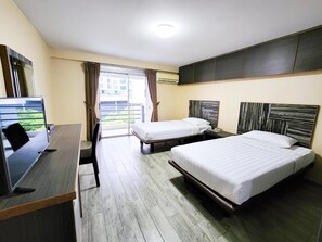 A hotel room with two beds, a desk, a TV, and a view of the outside. - Watana Hotel (Bangkok)