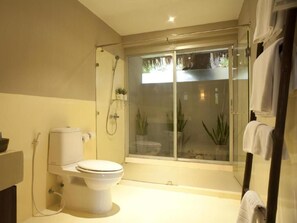 A modern bathroom with a toilet, shower, and glass-enclosed shower area. - Casuarina Beach Resort (Cha Am)