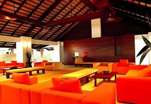 A spacious indoor area with orange seating, a wooden ceiling, and a large window. - Casuarina Beach Resort (Cha Am)