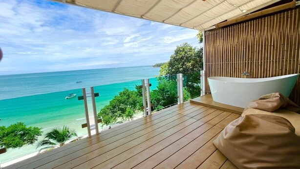 Una terraza de madera con vistas al océano y un área de spa con una bañera.
