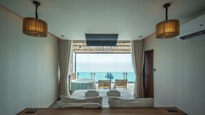 Habitación de hotel con cama, dos sillas, una mesa y vista al mar.