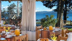 Une table de petit-déjeuner avec des meubles en bois, une vue sur la mer et une sélection de produits pour le petit-déjeuner.