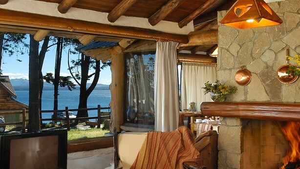 Un salon chaleureux avec une cheminée, un téléviseur et une vue sur le lac.