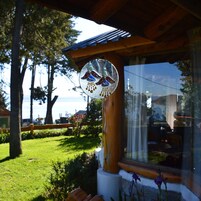 Un pabellón de madera con una ventana de vitral, un césped y vista al mar.