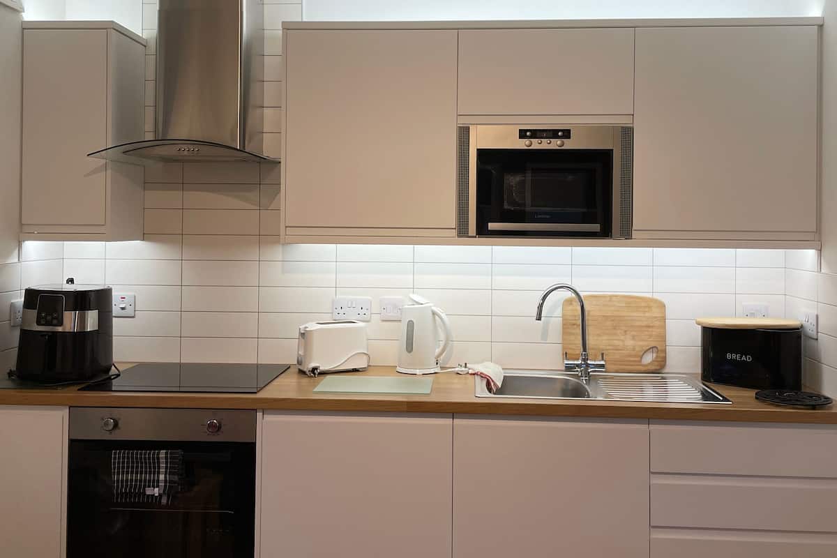 Uma cozinha moderna com armários brancos, eletrodomésticos de aço inoxidável e bancada de madeira.