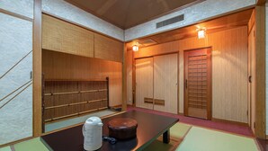 A traditional Japanese room with tatami flooring, a low table with a kettle and a thermos, and sliding wooden doors. - Aqua Garden Hotel Fukumaru (Kagoshima)