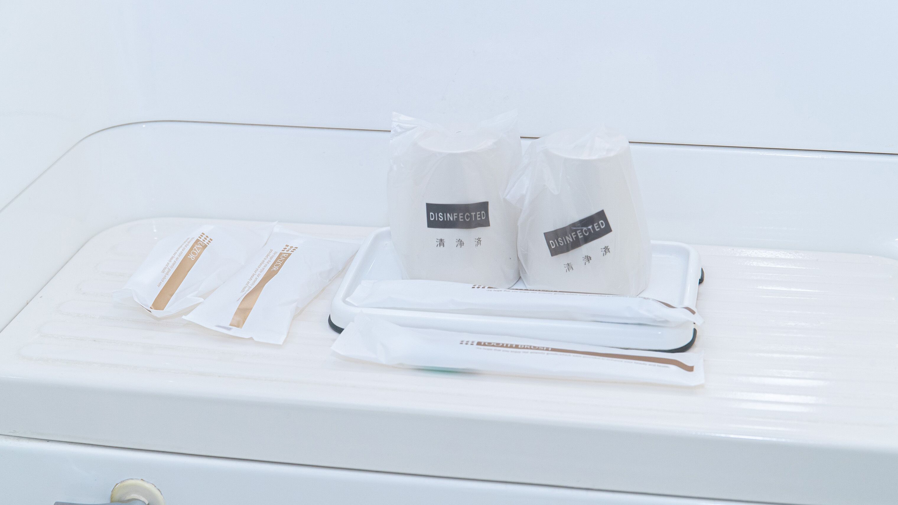 A white suitcase with two disinfected bags and a pair of slippers on top.
