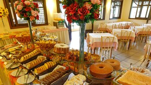 A buffet table with various food items and a floral centerpiece. - Palmas Hotel & Spa (Governador Celso Ramos)