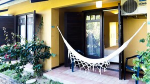 A yellow building with a hammock on the porch, a door, and a window. - Palmas Hotel & Spa (Governador Celso Ramos)