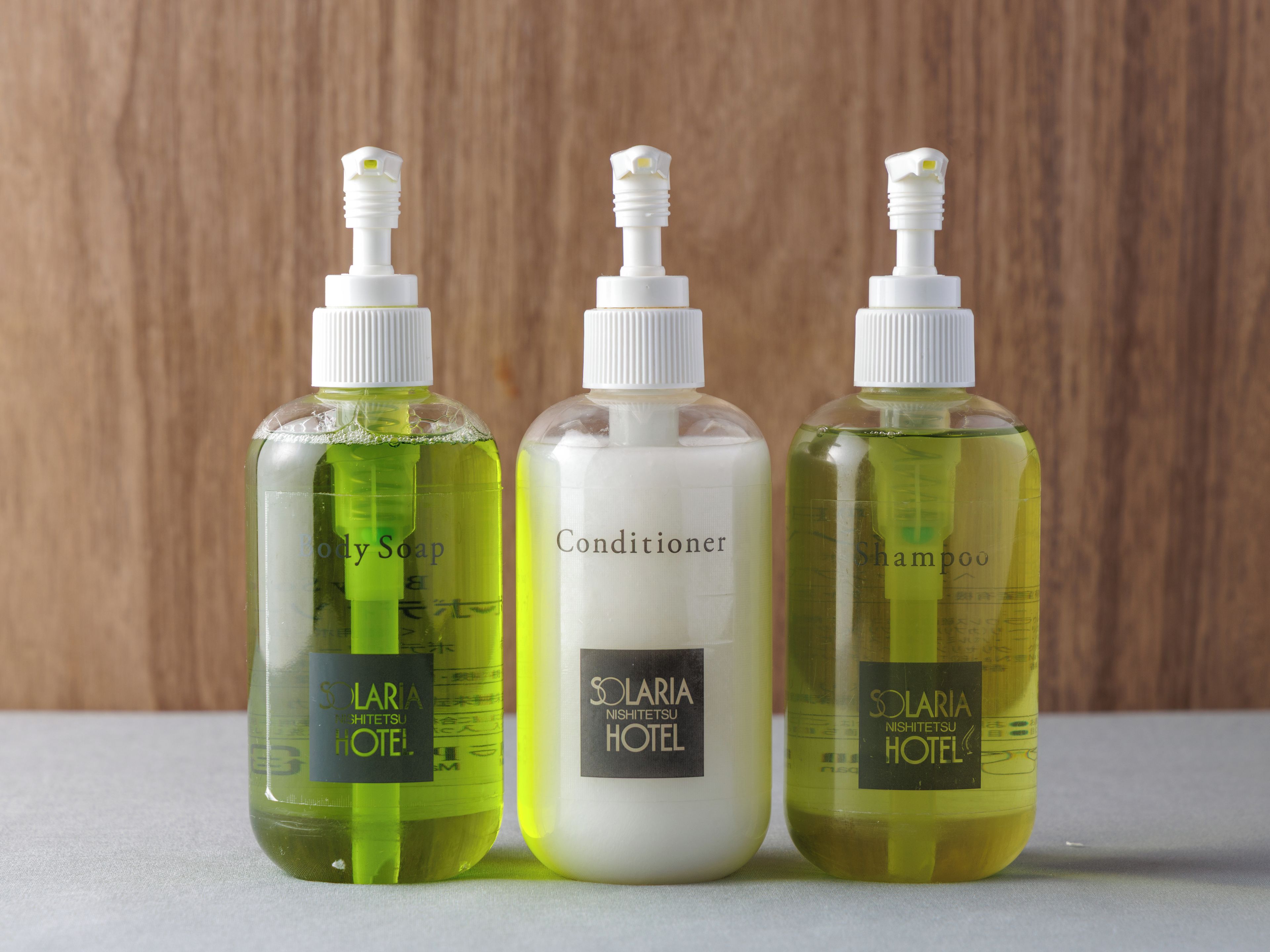 Three bottles of hotel toiletries on a surface.
