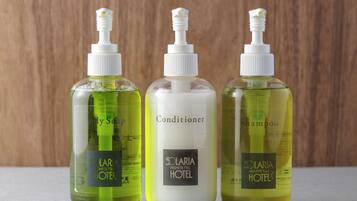 Three bottles of hotel toiletries on a surface.