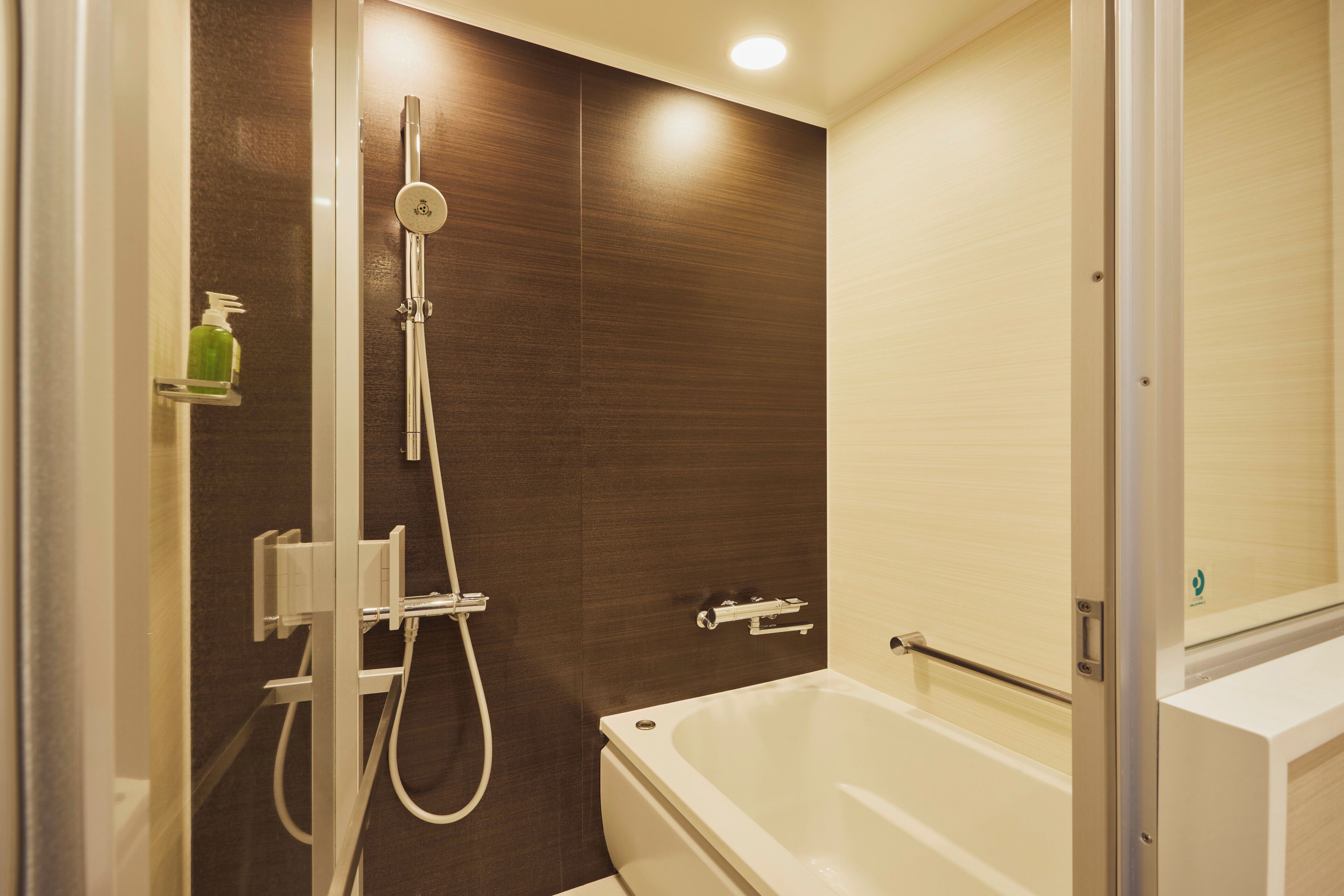 Ein modernes Badezimmer mit Badewanne, Dusche und einer Seifenspender auf einem Regal.