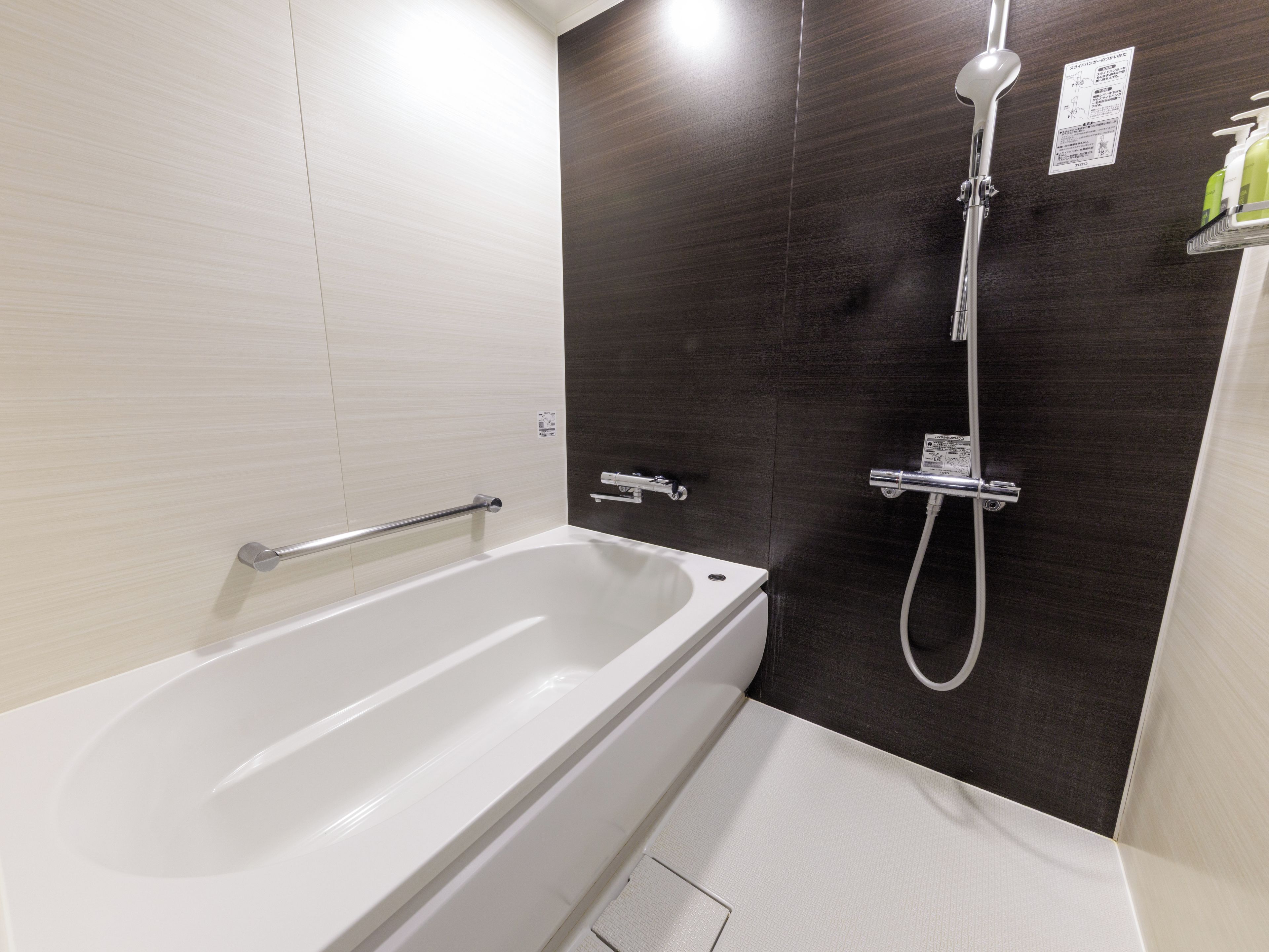 Une salle de bain moderne équipée d’une baignoire, d’une douche et d’une barre d’appui.