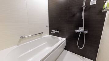 Une salle de bain moderne équipée d’une baignoire, d’une douche et d’une barre d’appui.