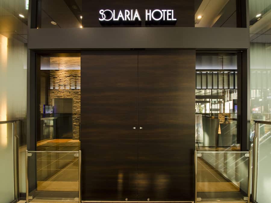 The entrance to Solaria Hotel with a modern design, featuring a dark wood facade and glass doors.