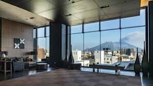 A spacious room with a large window offering a city view and a mountain in the distance. - Solaria Nishitetsu Hotel Kagoshima (Kagoshima)