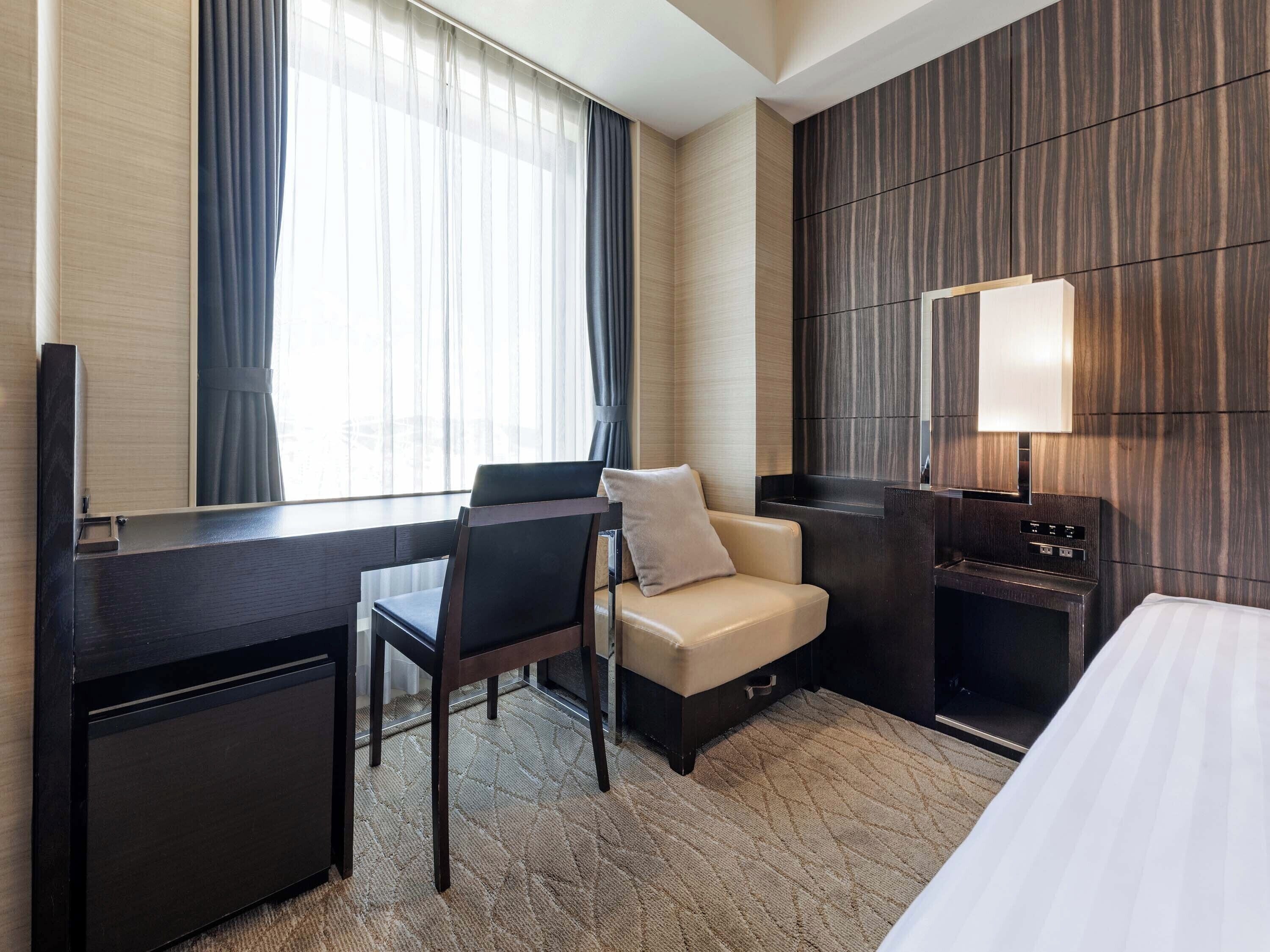 Una habitación de hotel con escritorio, silla, sofá y televisor.