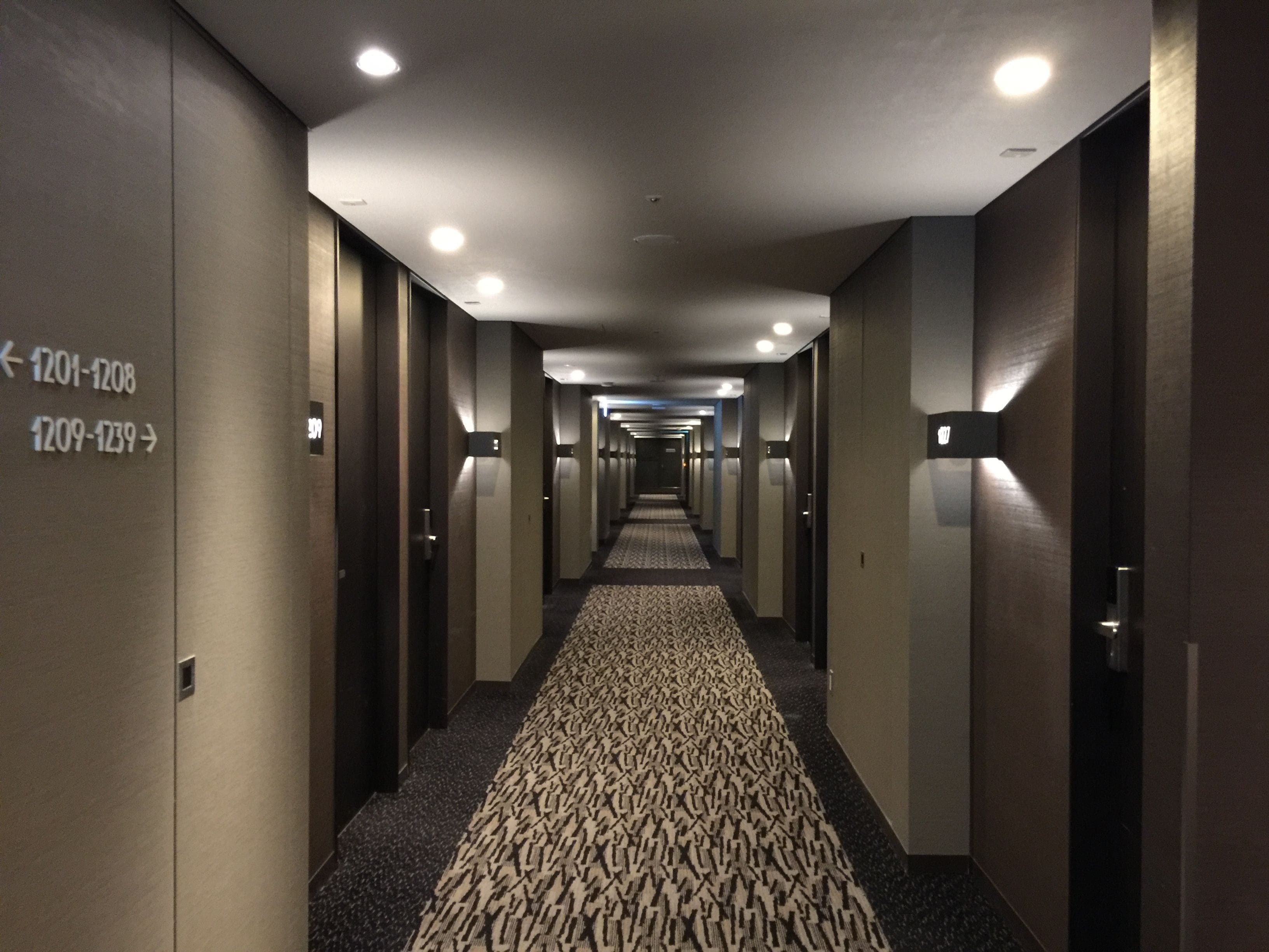 Un pasillo de hotel con señales direccionales indicando los números de habitación 1201-1208 y 1209-1239.