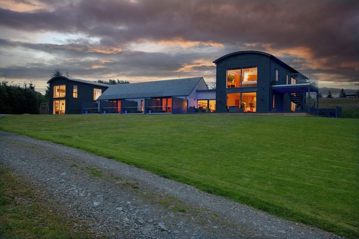 A modern house with large windows and a spacious lawn.