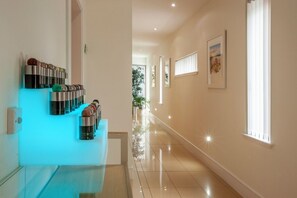 A hallway with a modern design, featuring a glass partition with decorative items, a light blue accent wall, and a framed picture on the wall. - Ardtorna (Oban)