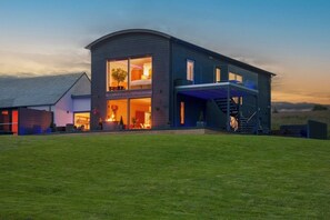 A modern two-story house with a large glass front and a staircase leading to an upper level. - Ardtorna (Oban)