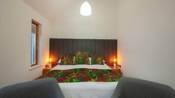 Un dormitorio con cama, dos mesitas de noche, una ventana y una lámpara colgante.