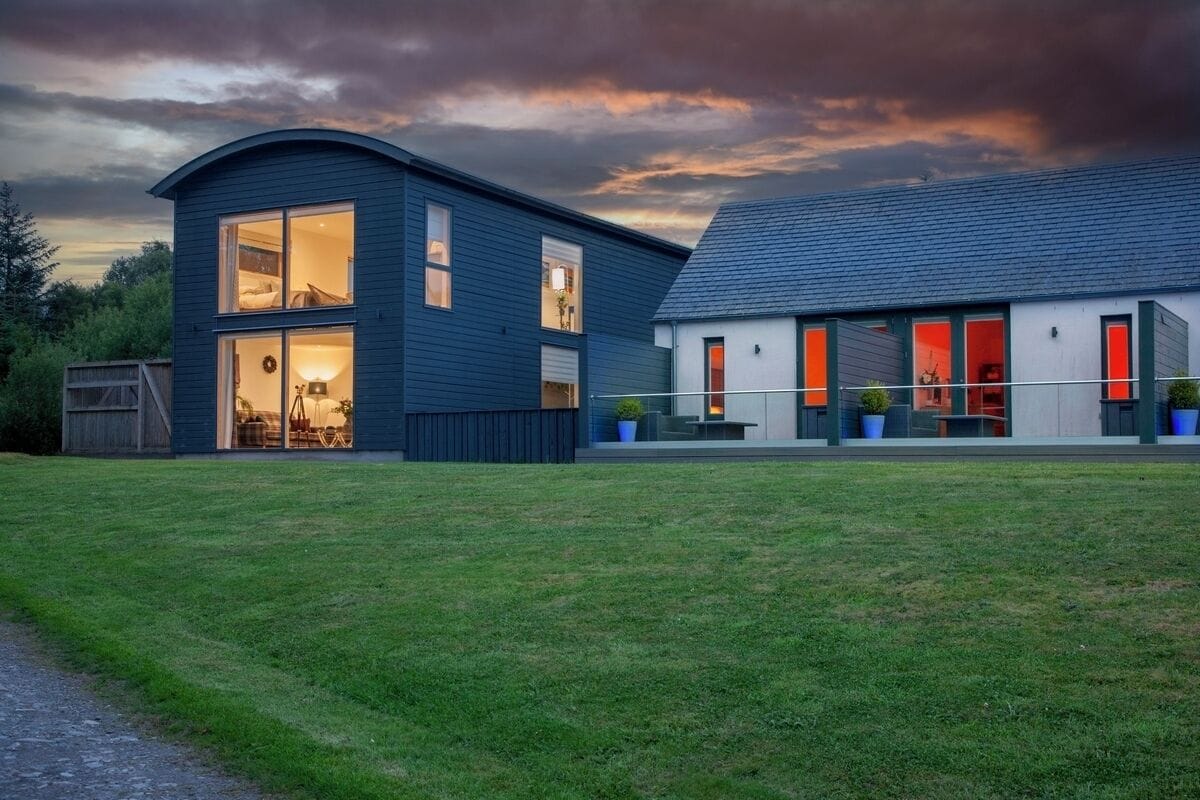 Une maison moderne à deux étages, dotée de grandes fenêtres et d’une pelouse bien entretenue.