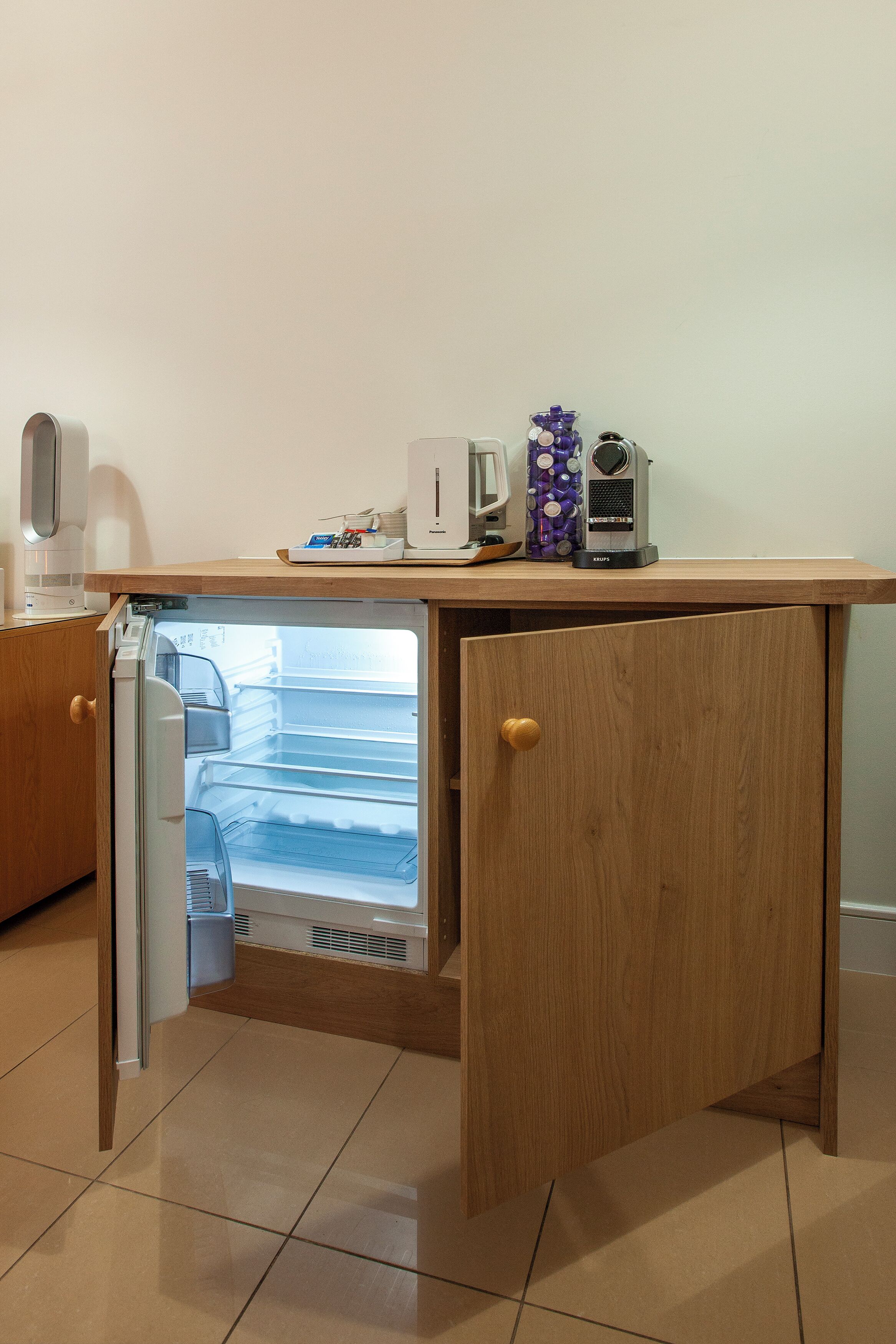 A compact kitchenette with a built-in refrigerator, a coffee maker, and a small sink.