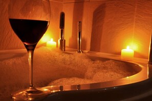 A glass of red wine, a bathtub filled with bubbles, and two lit candles in a warm, dimly lit room. - Ardtorna (Oban)