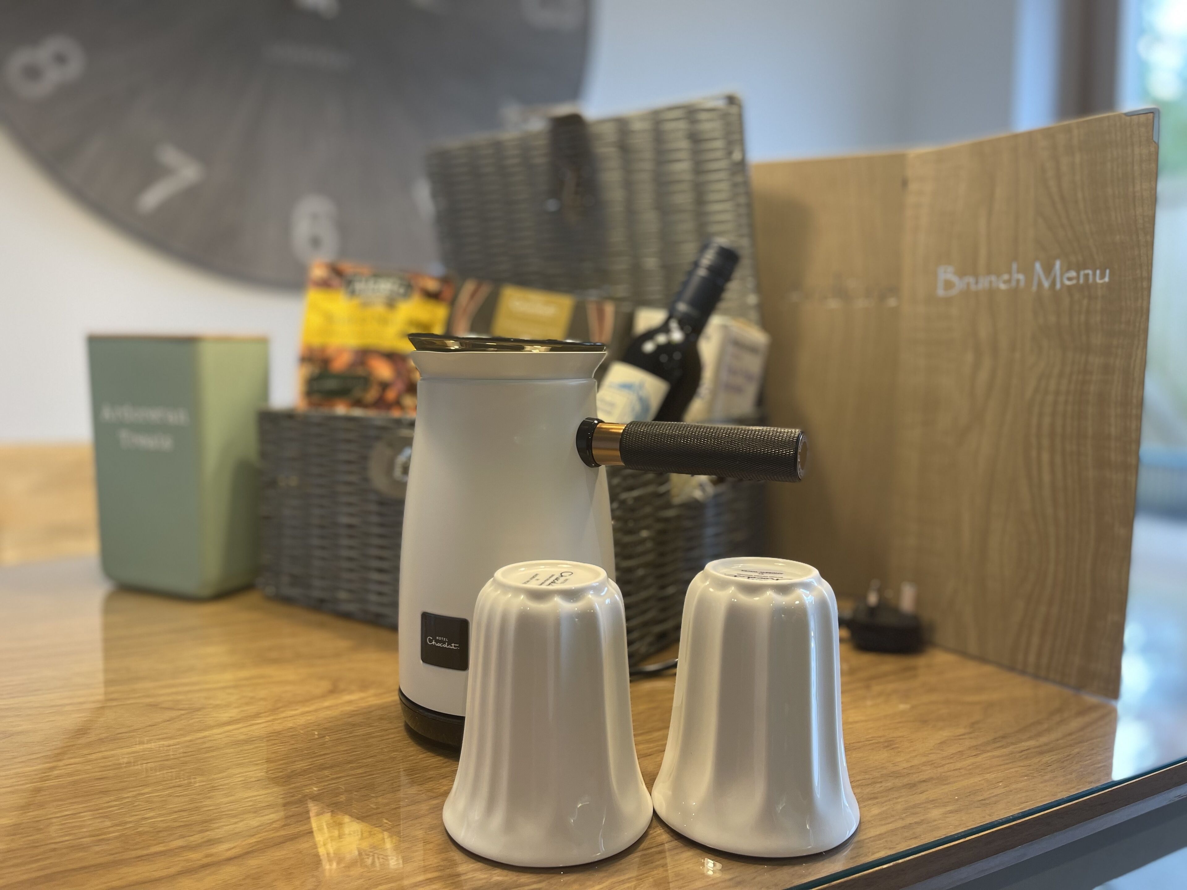 A kitchen area with a coffee maker, salt and pepper shakers, a basket, and a box labeled "Brunch Menu".