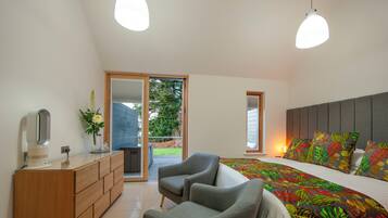 A bedroom with a bed, two chairs, a dresser, and a large window.