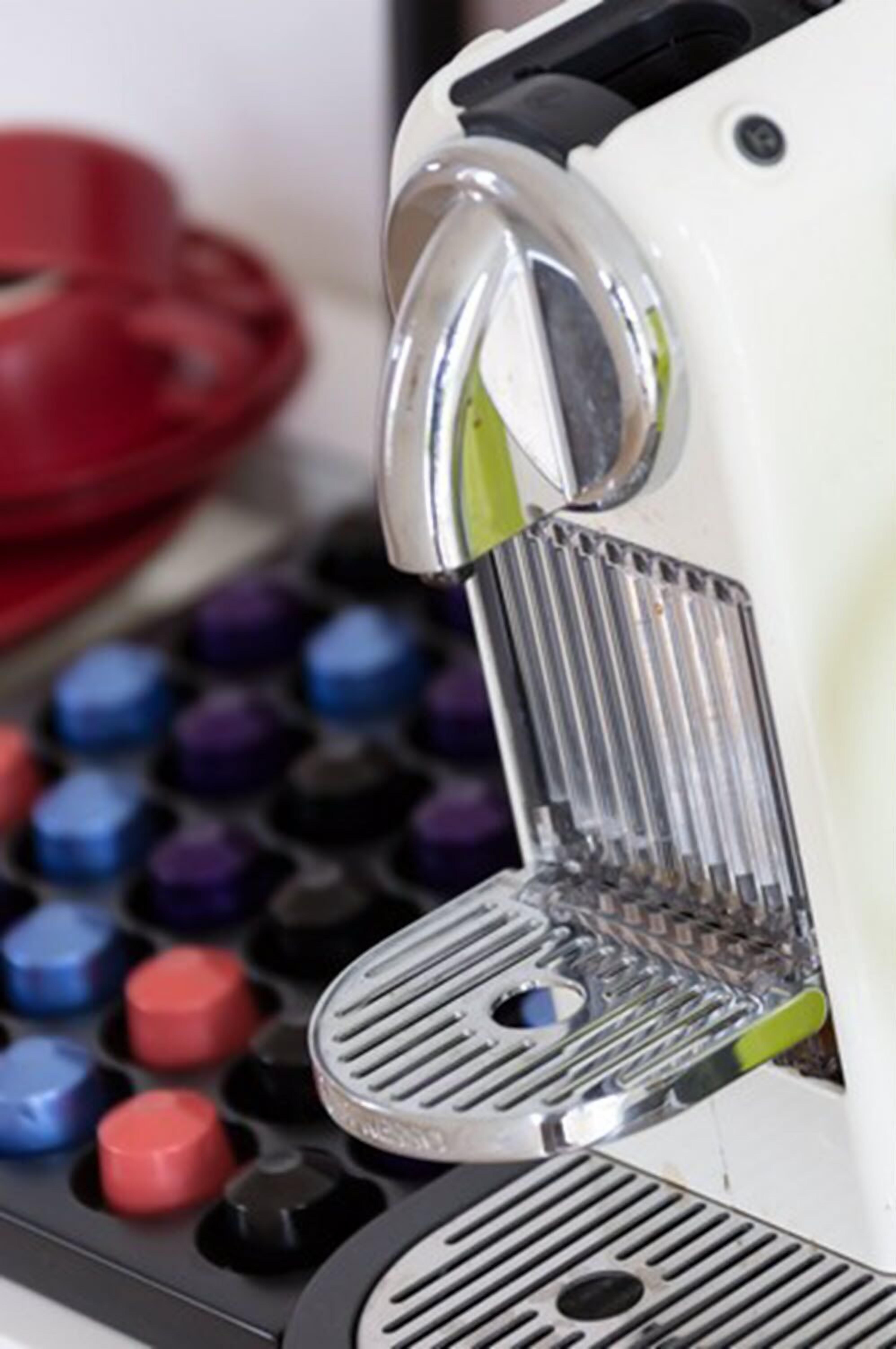 A close-up of a coffee machine with a metallic drip tray and buttons in various colors.