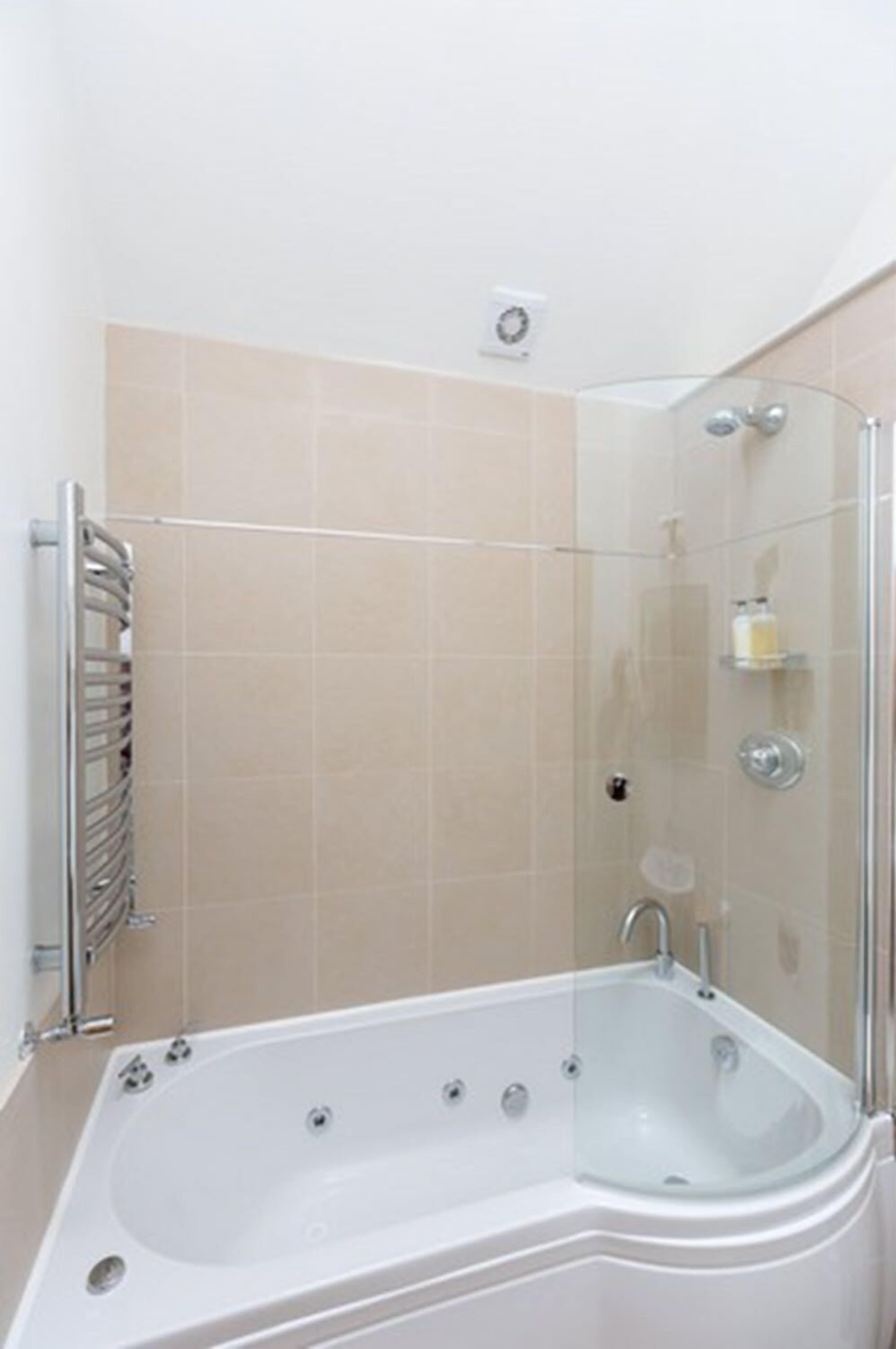 A modern bathroom with a glass-enclosed shower, a white bathtub, and a chrome towel rack.