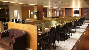 A modern restaurant with a long counter, leather seating, and a marble floor.