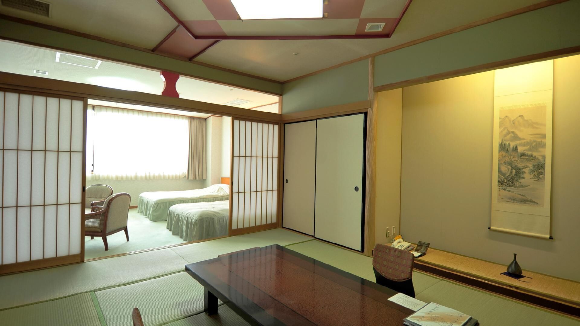 A traditional Japanese-style room with tatami flooring, a low table, and a sliding door leading to a bedroom.