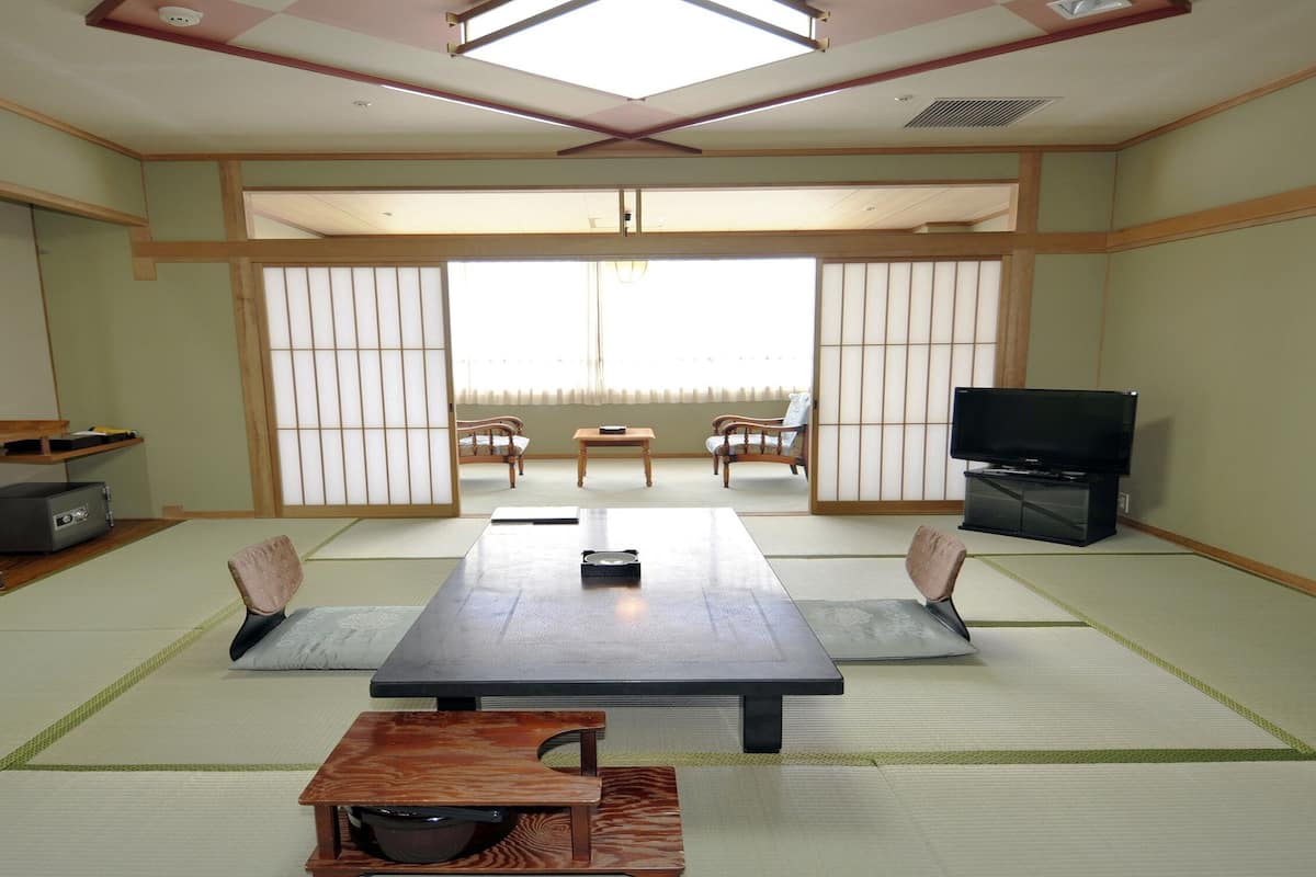Ein traditioneller japanischer Raum mit Tatami-Bodenbelag, einem niedrigen Tisch und verschiebbaren Türen.