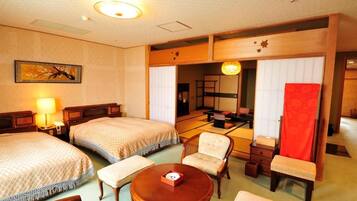 Habitación de hotel con dos camas, una zona de estar con mesa y sillas, una cortina roja y una puerta corrediza tradicional japonesa.