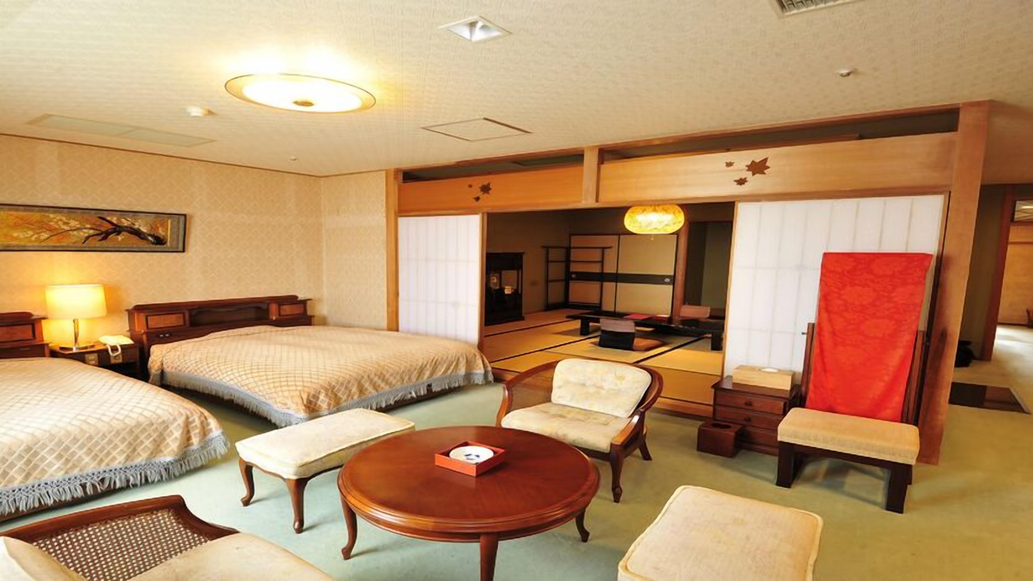 Une chambre d’hôtel avec deux lits, un coin salon avec une table et un grand miroir.