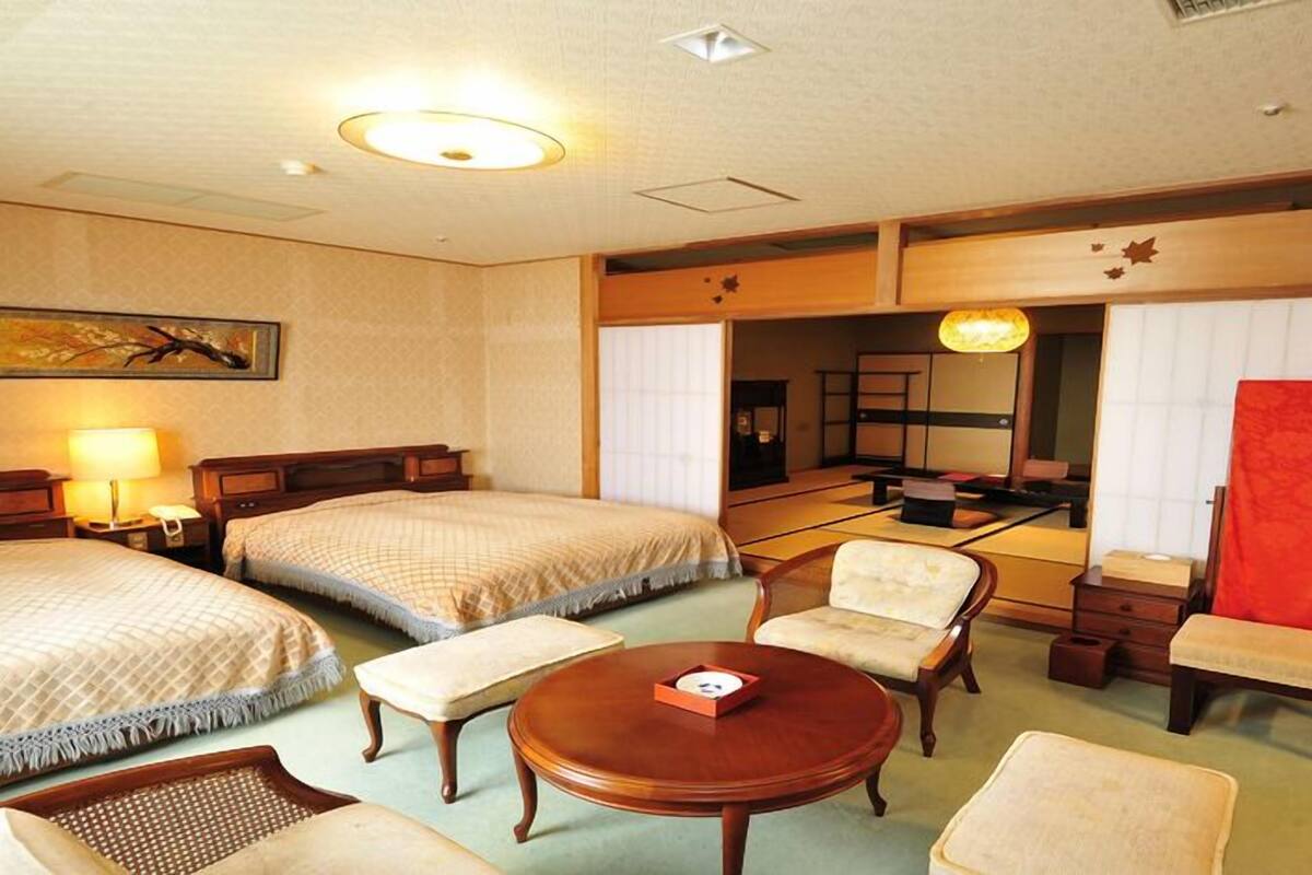 Ein Hotelzimmer mit zwei Betten, einer Sitzecke mit Tisch und einem großen Spiegel.